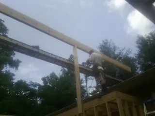 Carpenter setting a ridge beam over a new addition frame — Ice Dam Removal by Roofing Brothers in Junction