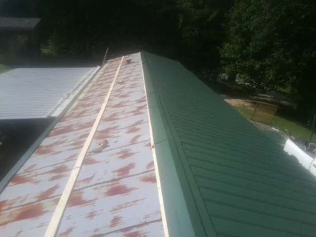 Old rusted panels beside newly installed green metal roofing — Wind Damage Roof Repair by Roofing Brothers in Junction