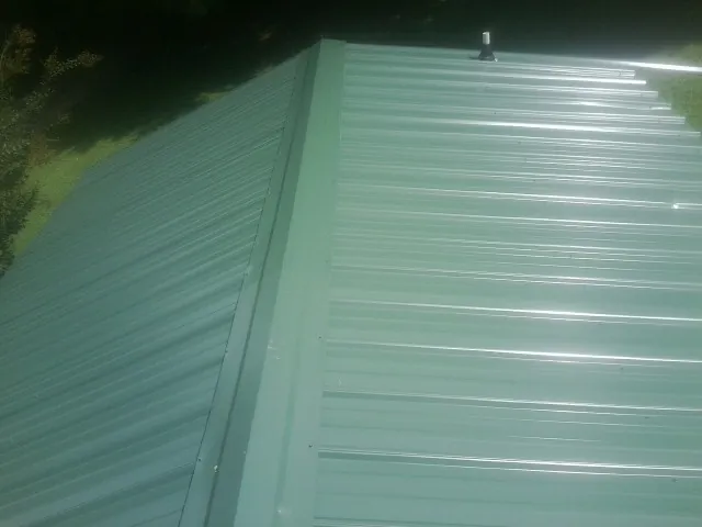 New green metal panels meeting at the ridge of a roof — Flat Roof Repair work by our crew in Junction