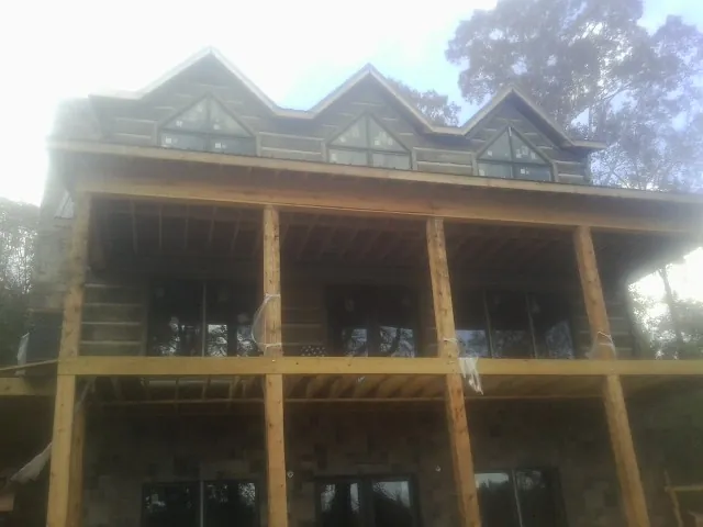 Dormers and porch framing on a large log home under construction — Roof Coating work by our crew in Junction