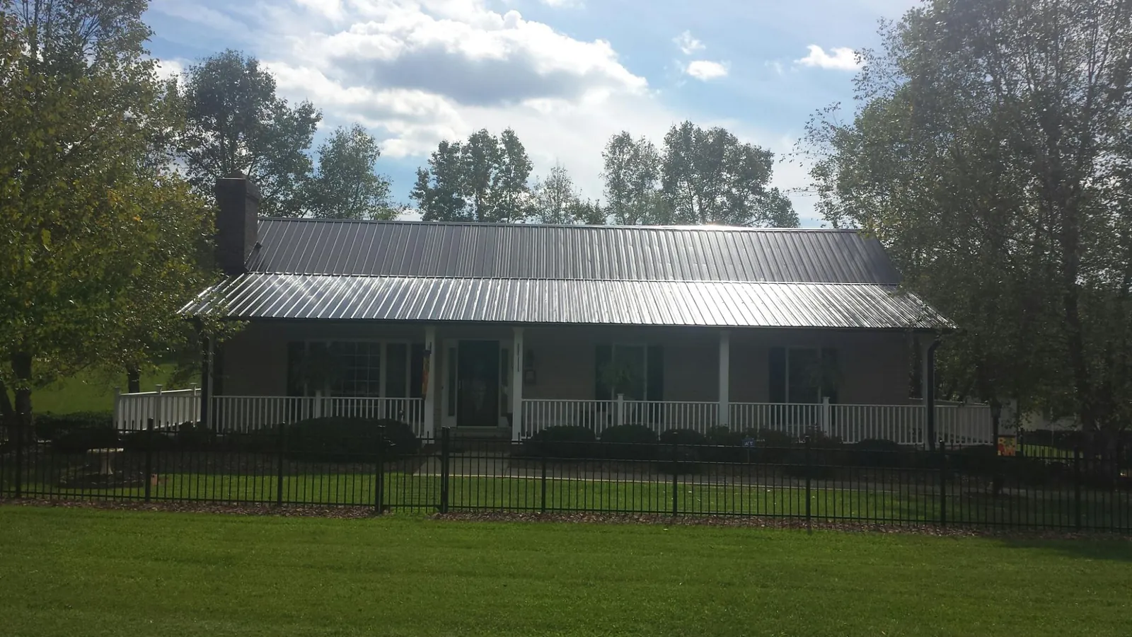 Gray metal roof on a brick ranch with a full width front porch — Gutter Guard Installation work by our crew in Junction
