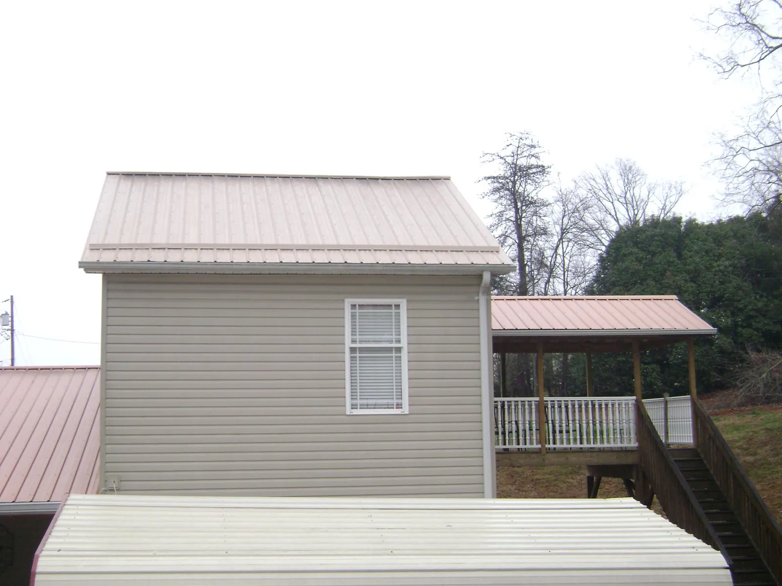 Tan metal roofs on a two story addition and attached porch, from a Roof Replacement job in Junction